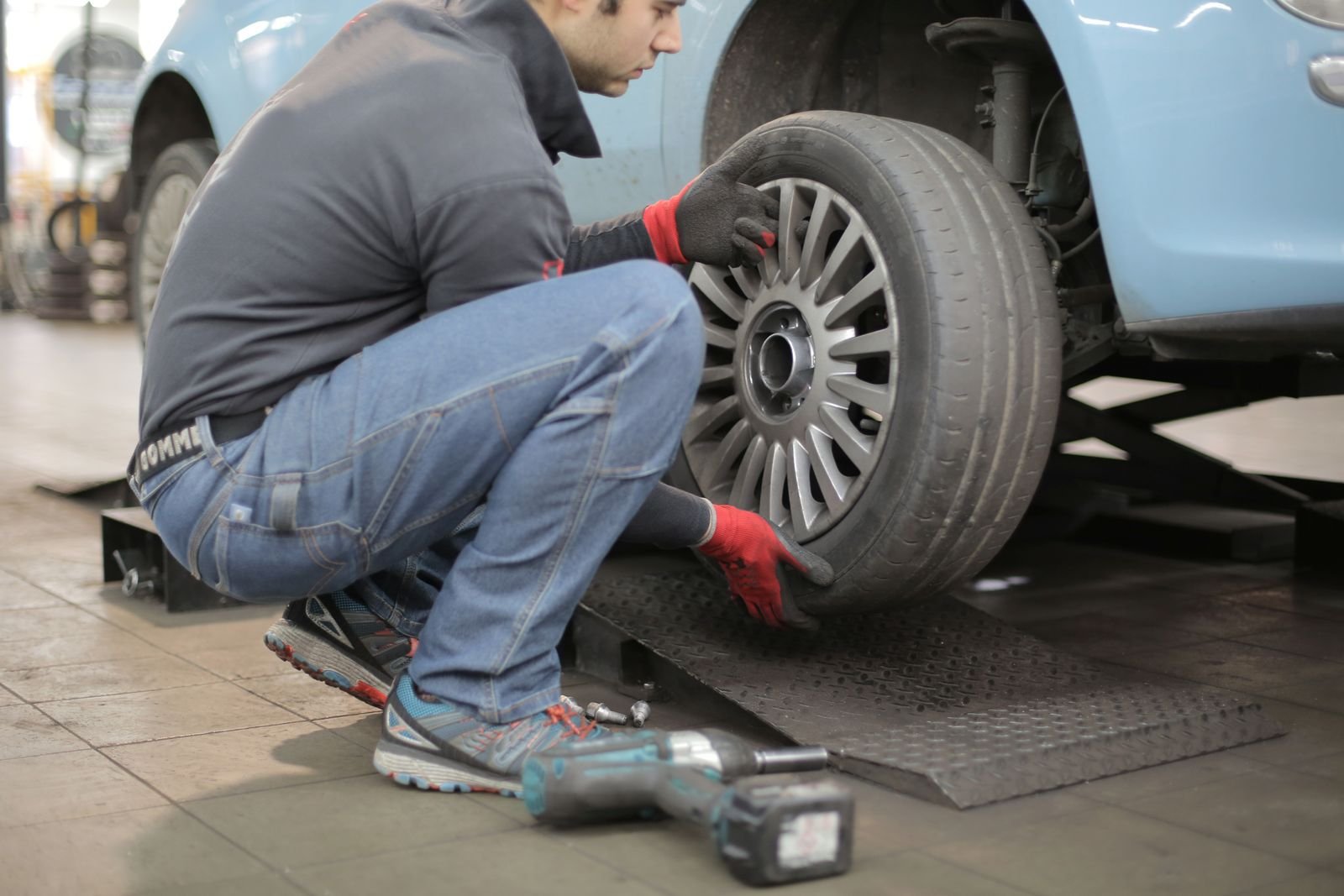Mechanic fitting a tire to a vehicle in an auto repair shop